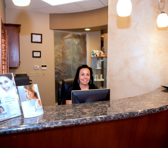 Smiling Gilbert dental team member at reception desk