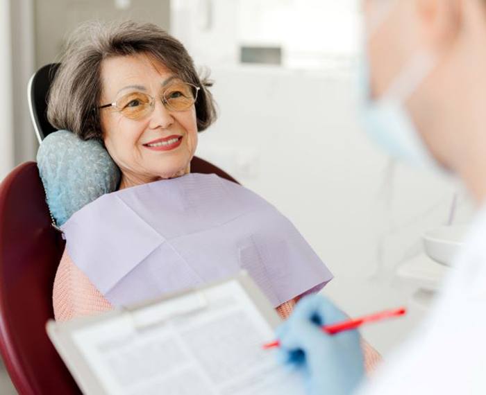 Dentist taking notes during senior patient’s consultation
