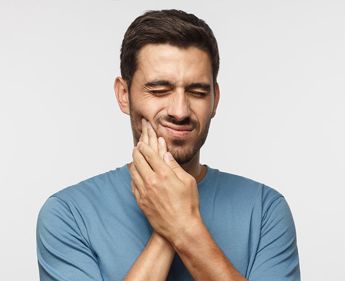 Man wincing in pain while holding his face