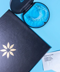 Invisalign next to packets of cleaning crystals on light blue background