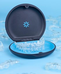 Invisalign in carrier case surrounded by multiple clear aligners on blue background