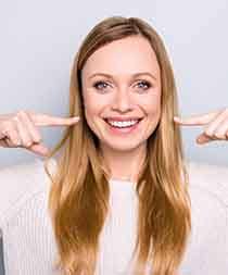 Smiling woman pointing to her mouth