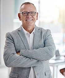 Man in grey suit smiling with arms folded