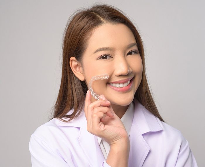 Woman smiling while holding clear aligner