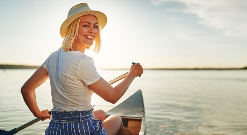 Woman smiling while canoeing on lake in the summer